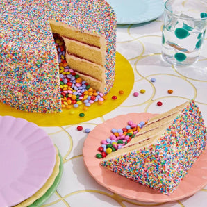 Pinata Cake with colorful rainbow sprinkles and mini Smarties spilling out from vanilla sponge layers.